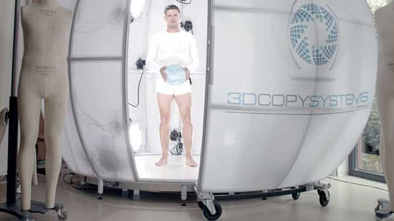 Man holding ball and standing inside 4D scanner at Hohenstein Digital Fitting Lab