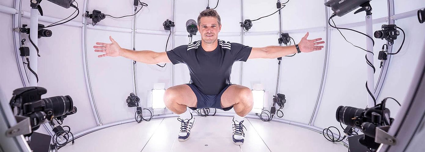 4D Scanning to Measure Fit in Motion at Hohenstein Man squatting in 4D scanner with arms spread wide at Hohenstein